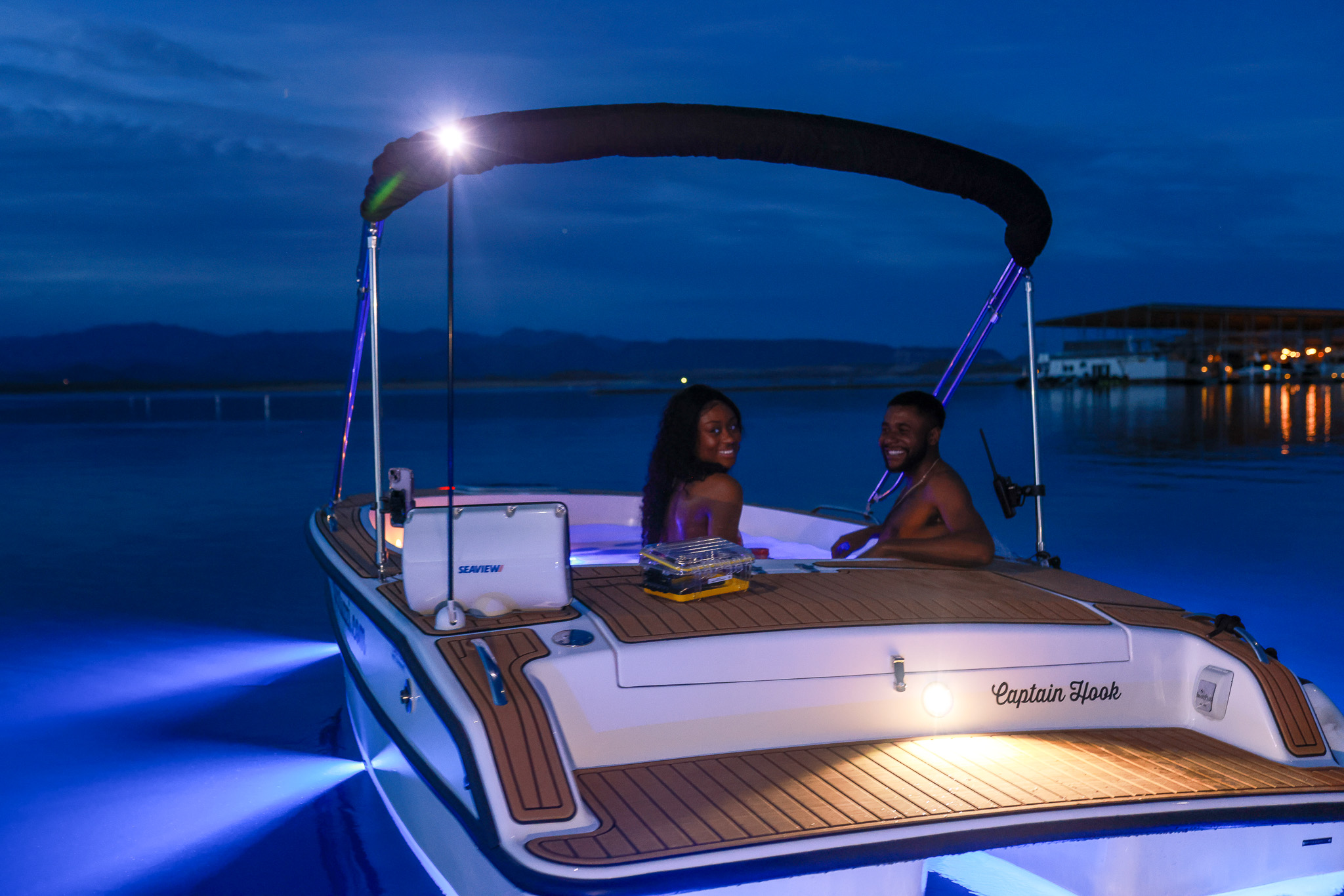 Couple relaxing in a Yachtuzzi hot tub boat at night on Lake Pleasant with blue LED lighting